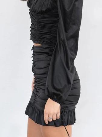 Black satin mini skirt with ruffles and drawstring waist, shown on a model.