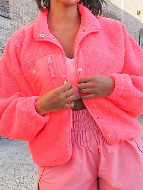 Bright pink fleece jacket with snap buttons, shown worn outdoors.