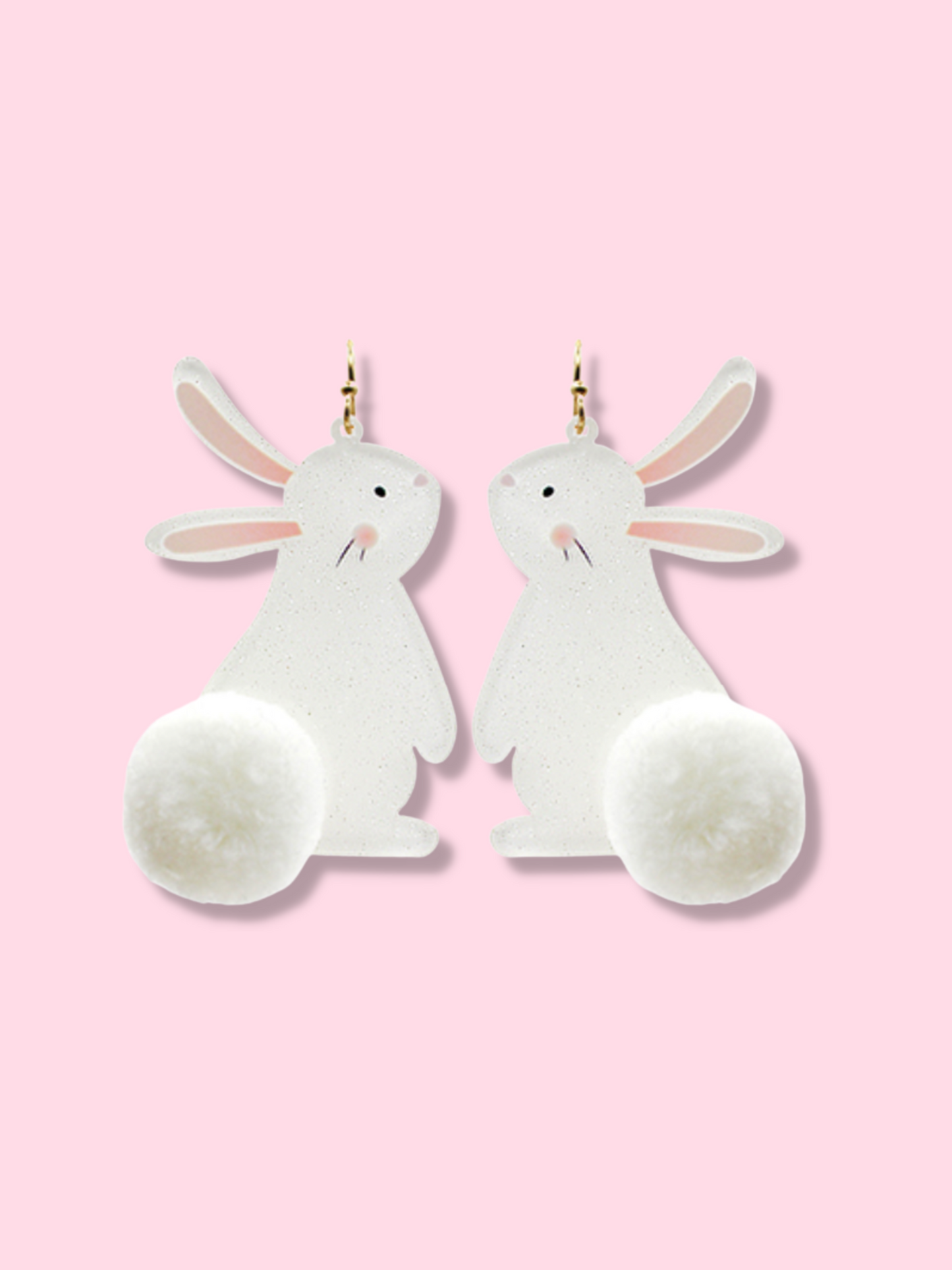 Adorable white bunny earrings with fluffy pom-pom tails, shown against a pink background.