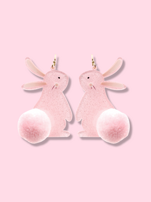 Pink bunny rabbit dangle earrings with fluffy pom-pom tails, shown against a light pink background.