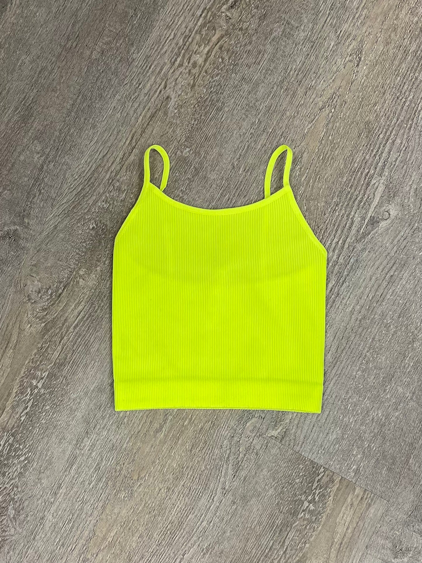 Bright neon yellow ribbed tank top on gray wood background.