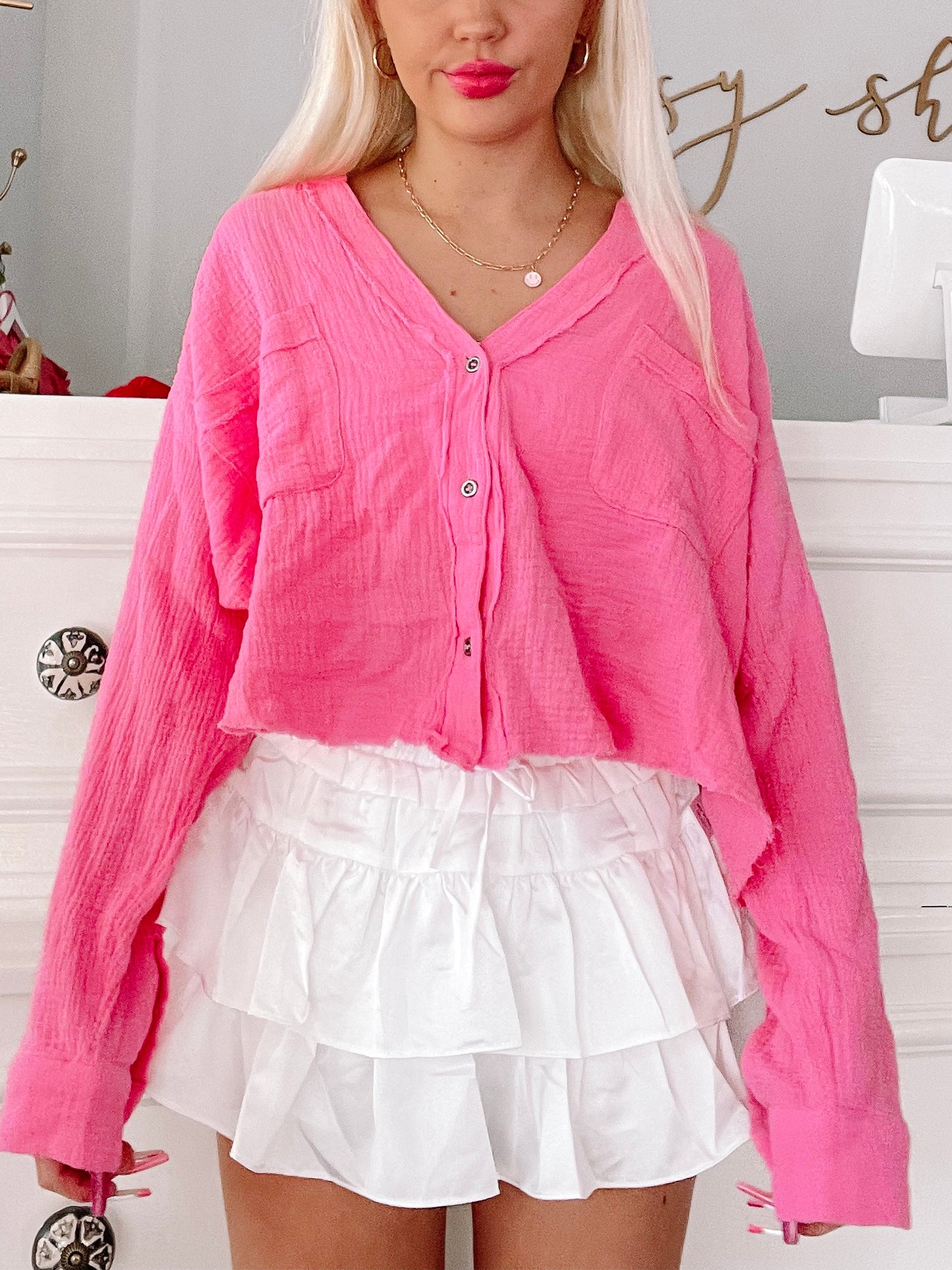 Hot pink button-up top and white ruffled mini skirt.