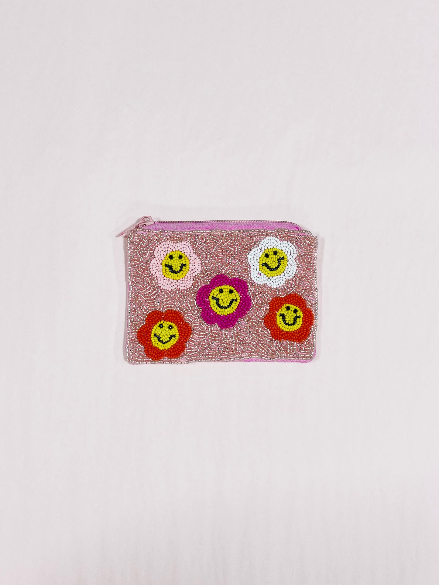 Pink beaded pouch with smiling flower accents.
