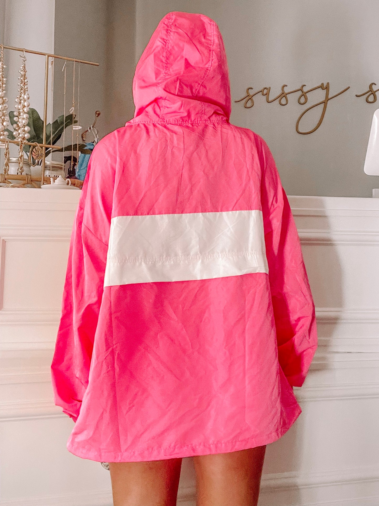 Hot pink windbreaker with white paneling, shown from the back against a light-colored wall.