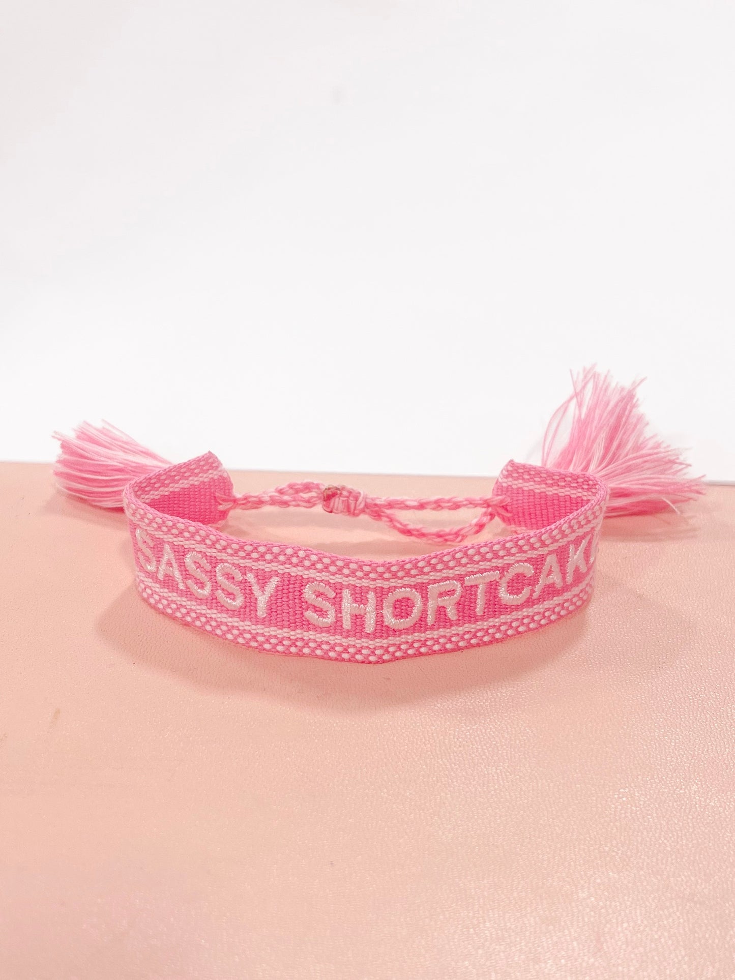 Pink "Sassy Shortcake" woven bracelet with tassels.