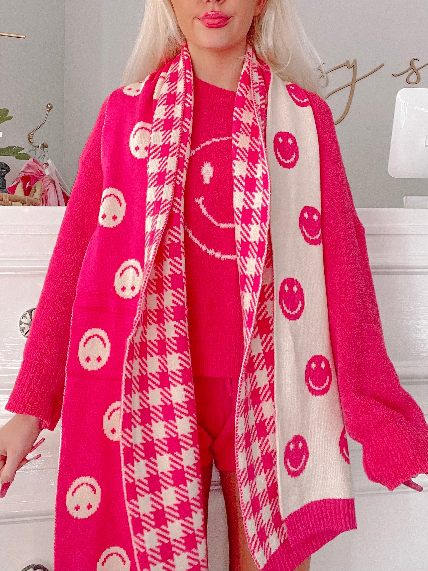 Hot pink and cream knit scarf featuring a cheerful smiley face pattern and houndstooth trim.