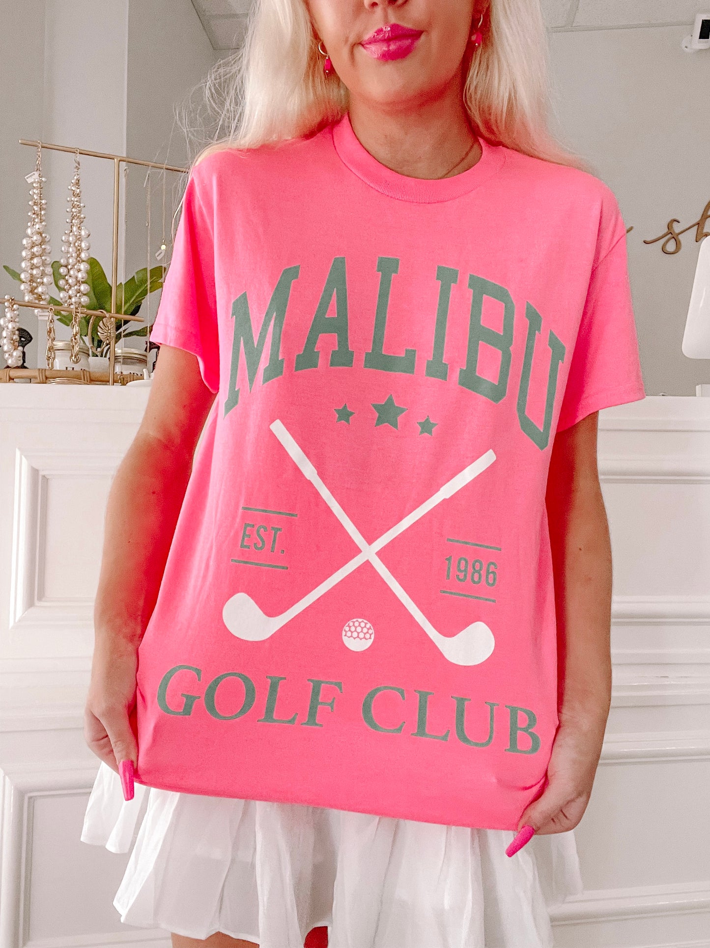 Hot pink tee showcasing a golf club graphic, "Est. 1986" detail.