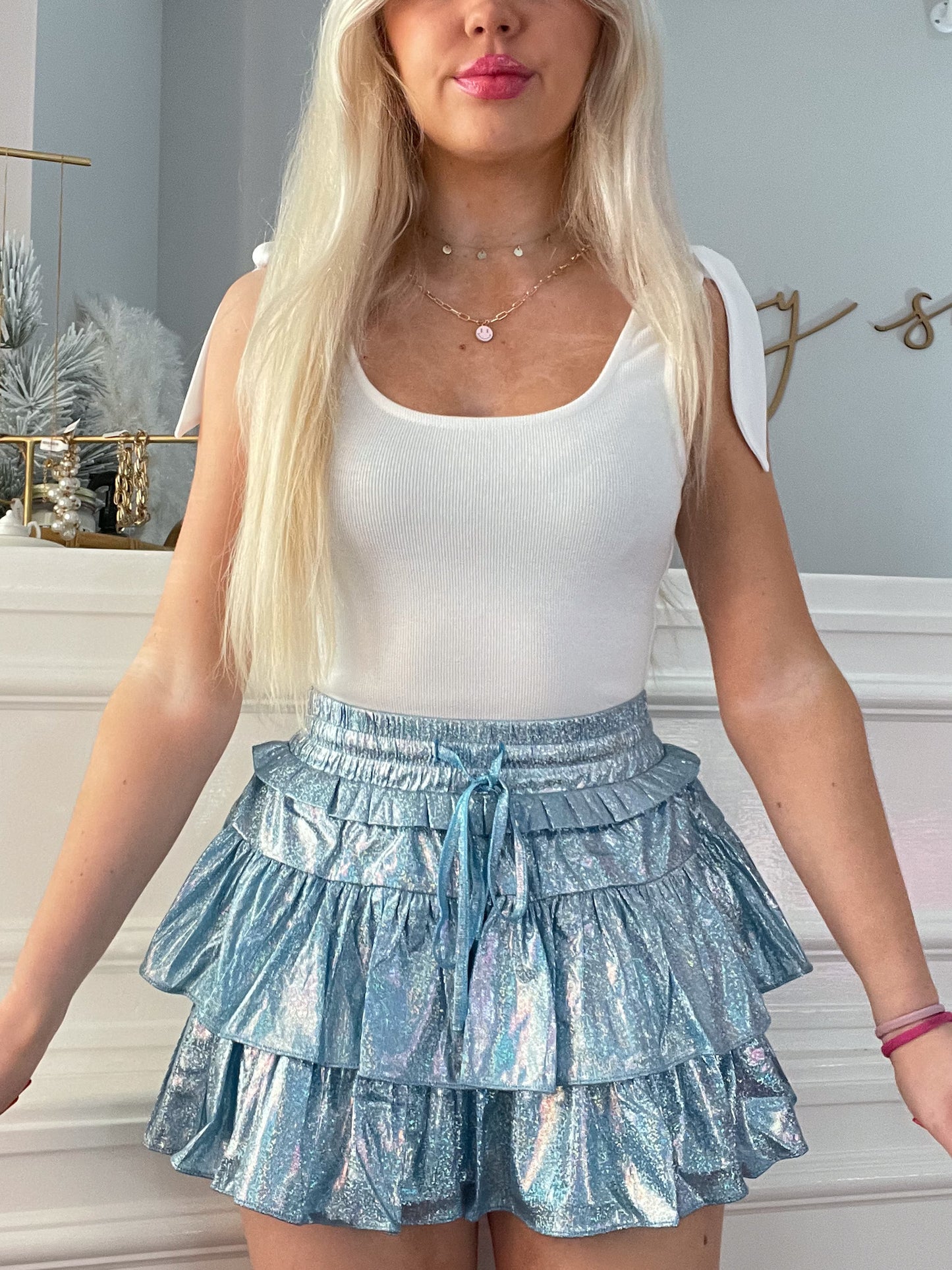 Light blue iridescent tiered mini skirt with drawstring waist, modeled indoors.