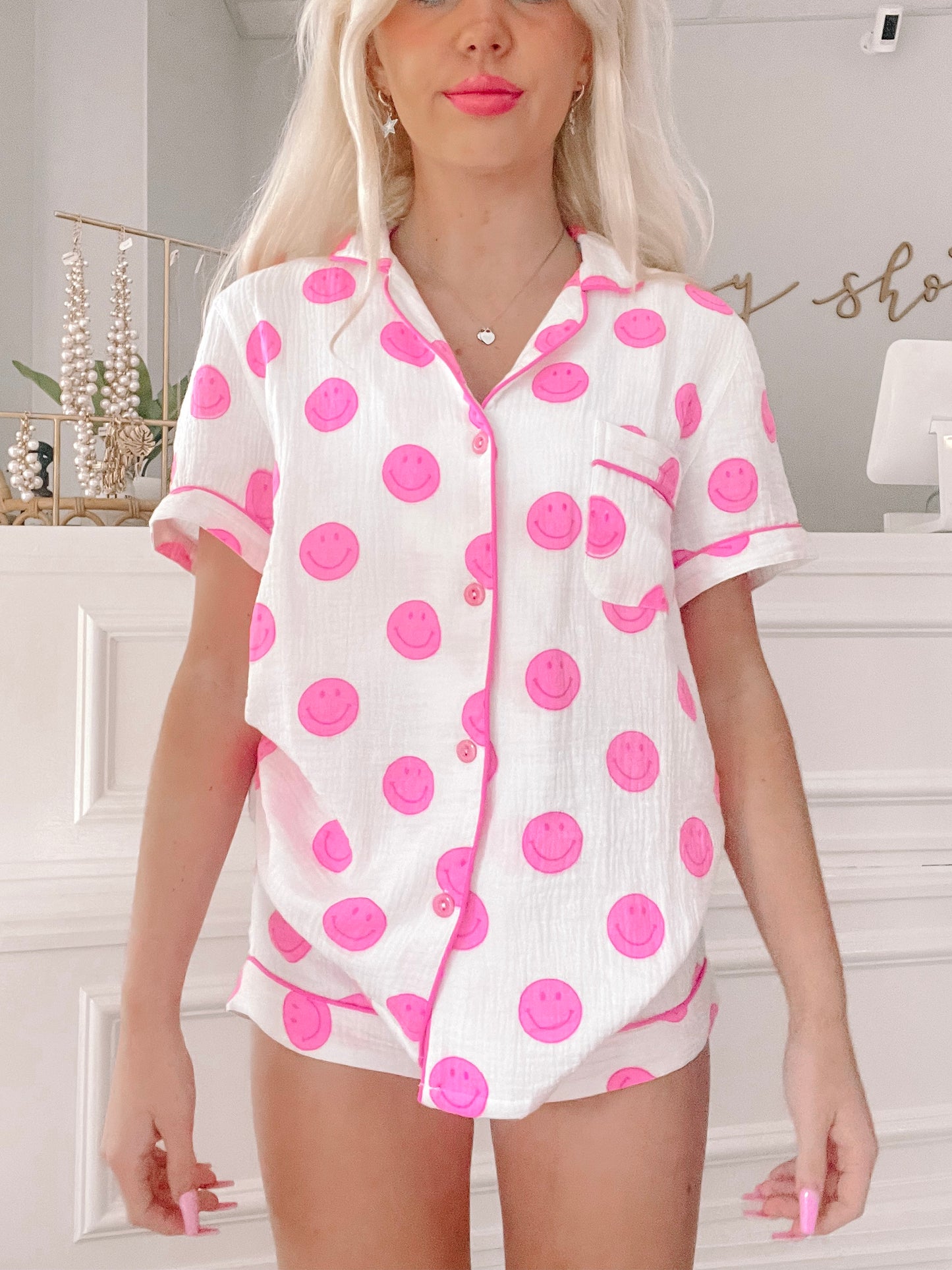 Pink smiley face pajama set; short-sleeved top and shorts, white background.