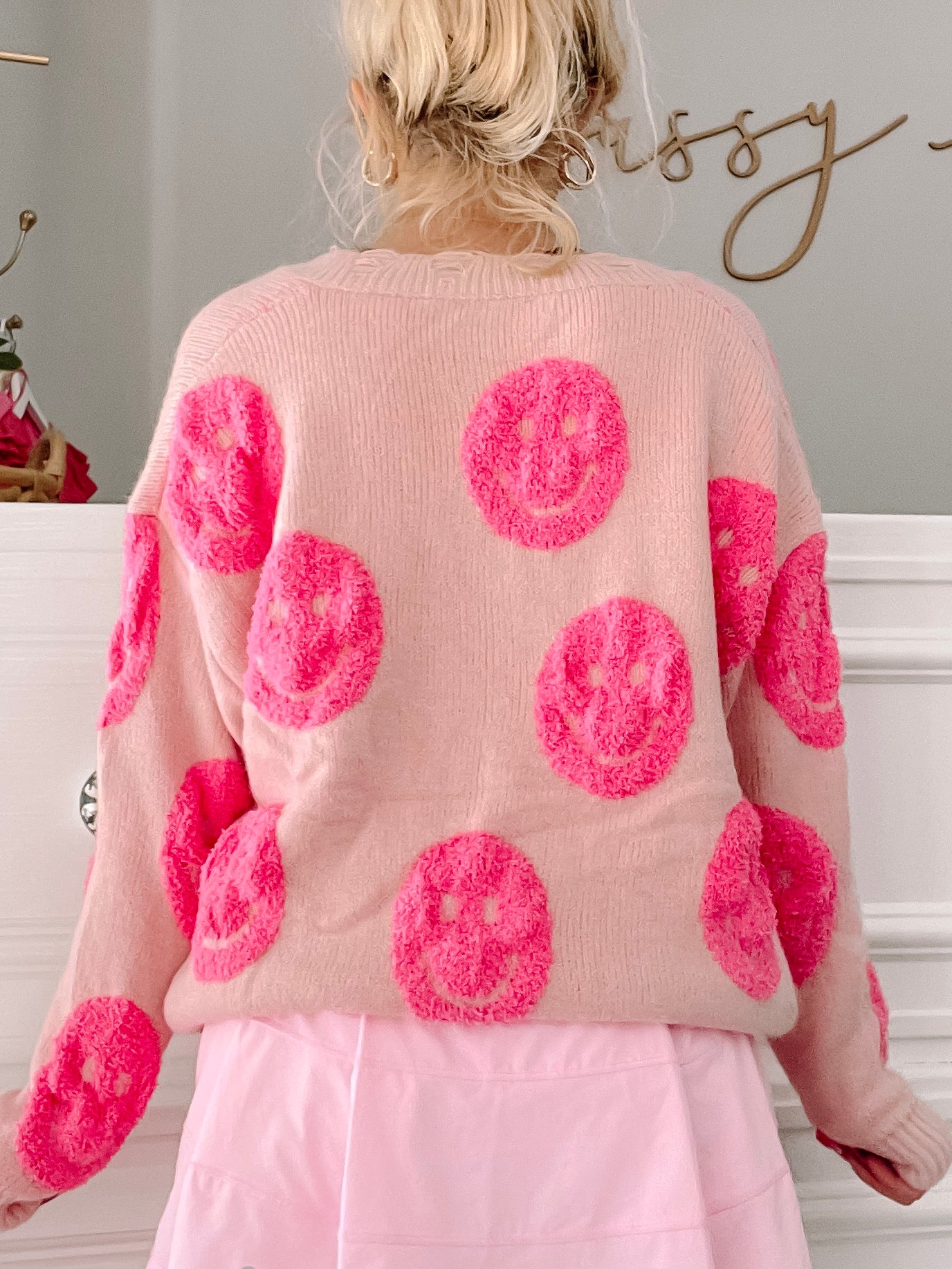 Pink sweater adorned with fluffy hot pink smiley faces.