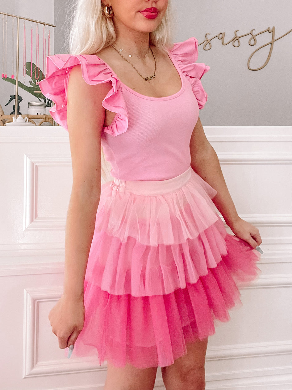 Pink layered tulle mini skirt and ruffled pink top; stylish outfit.