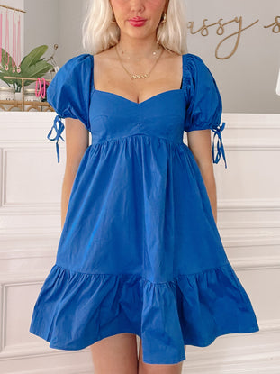 Blue mini dress with puff sleeves and tiered ruffle hem, shown on a model.