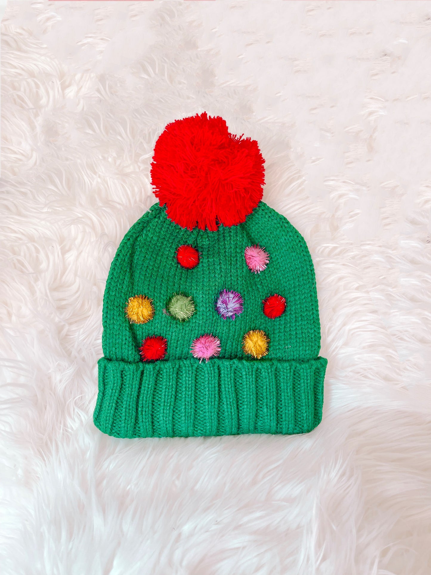 Green knit Oh Christmas Tree beanie with colorful pom-poms and large red pom-pom top.