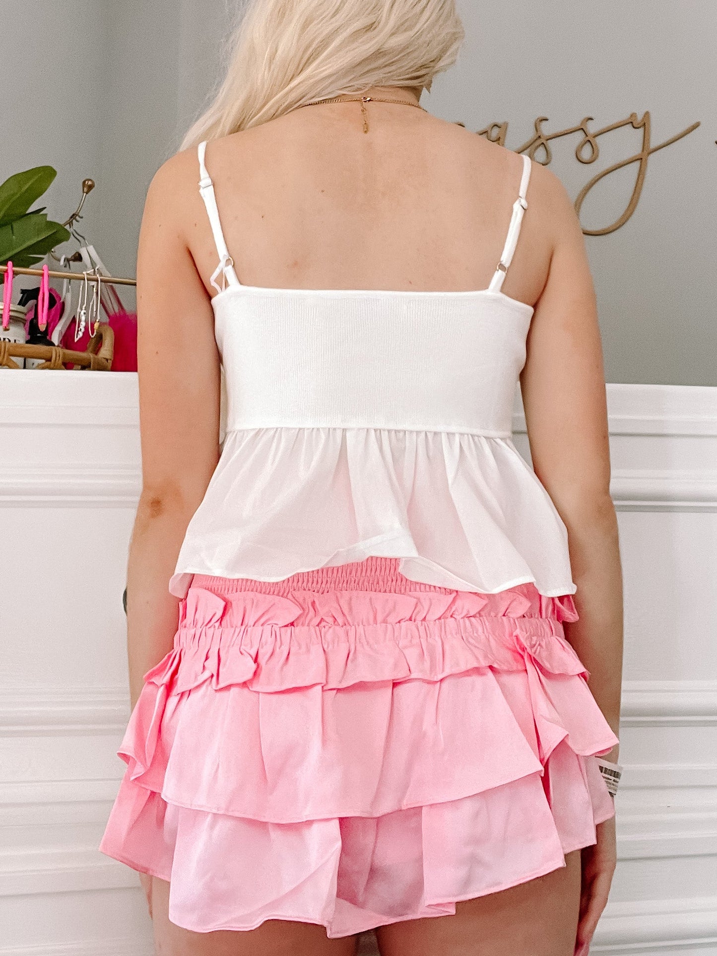 White cropped tank top and pink ruffled shorts, shown from the back.