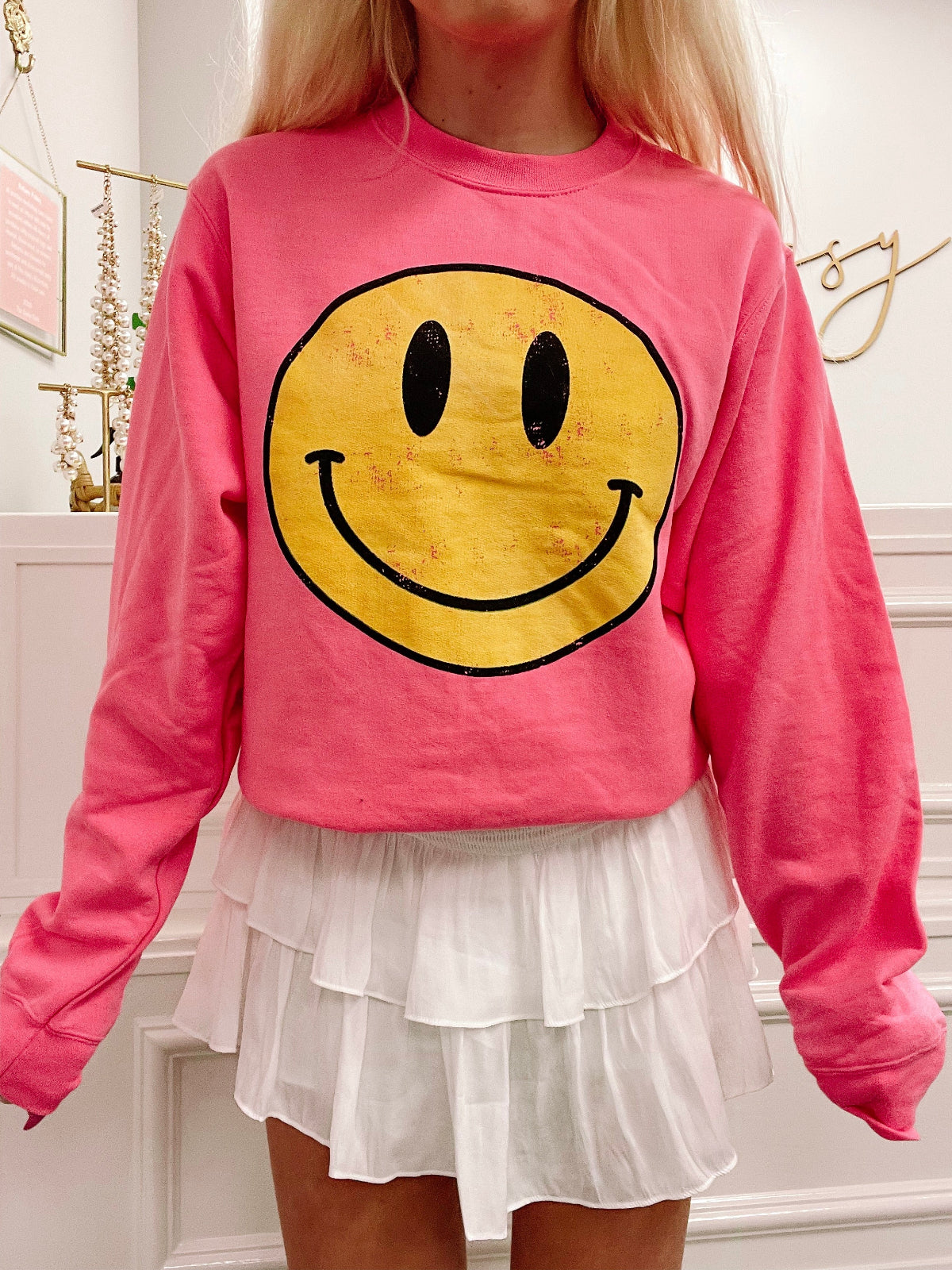 Pink sweatshirt featuring a vintage-style yellow smiley face graphic from Sassy Shortcake