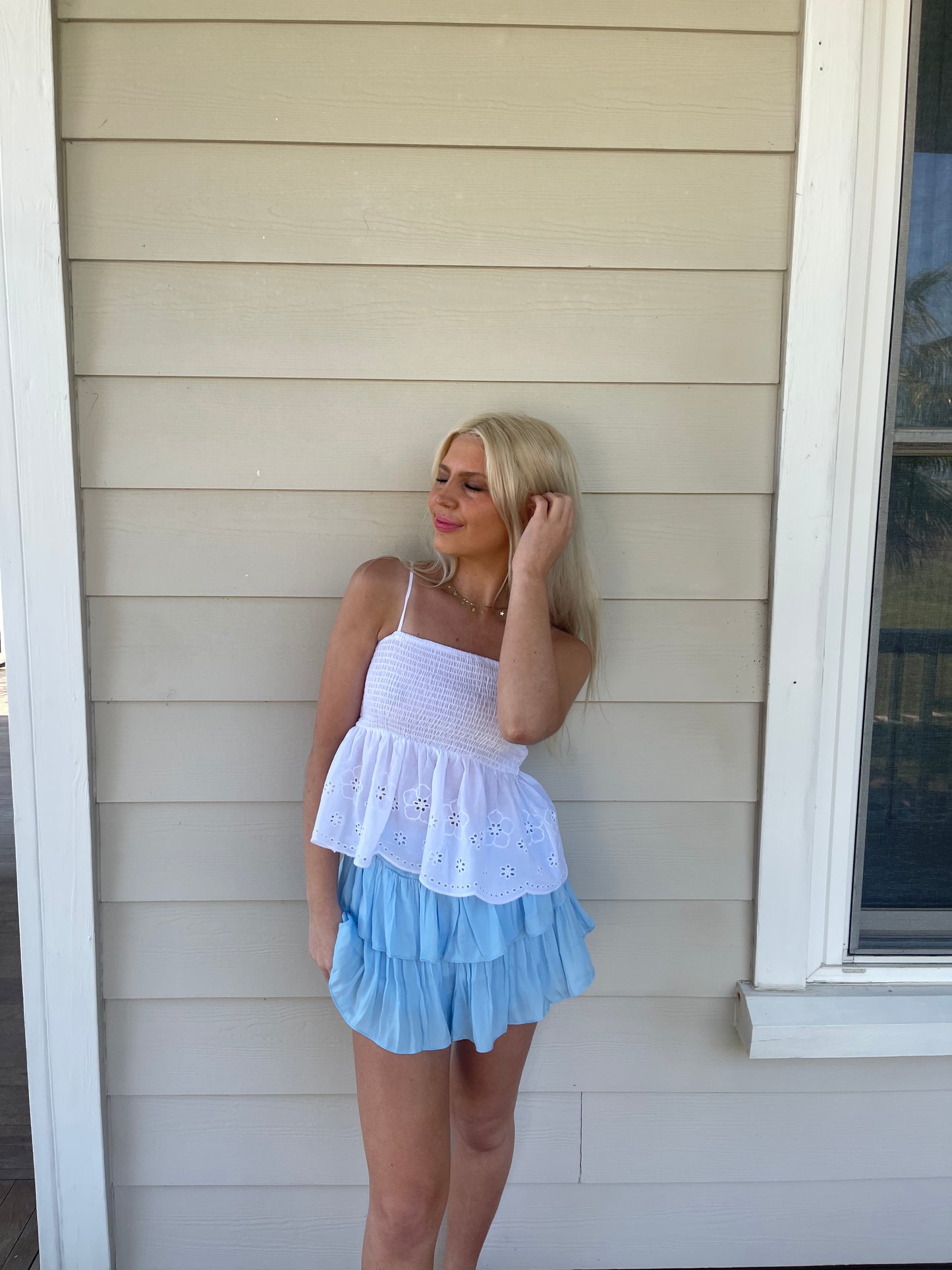 Sky blue tiered mini skirt; layered ruffle design, worn outdoors against light beige siding.