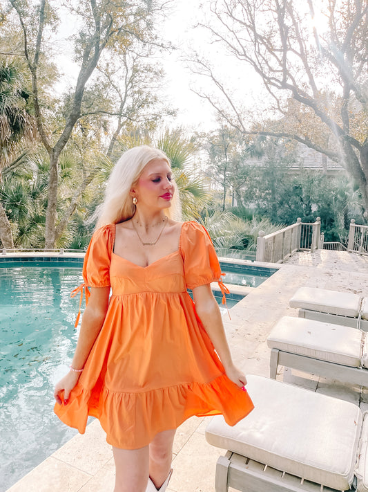 Woman in orange summer dress by the pool