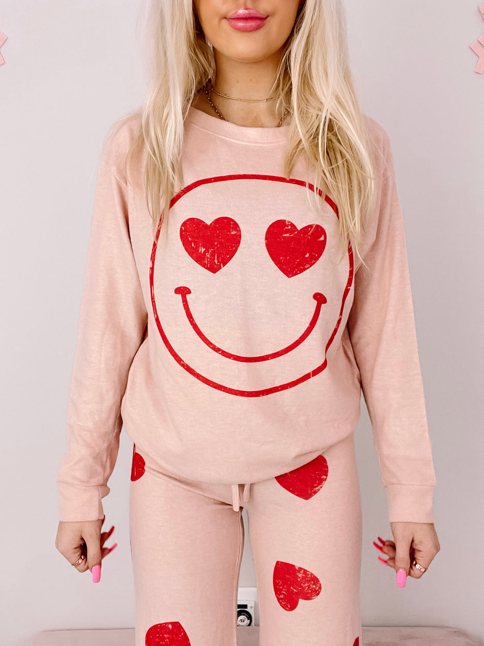 Pink pajama set with a red smiley face and heart print; cozy loungewear.