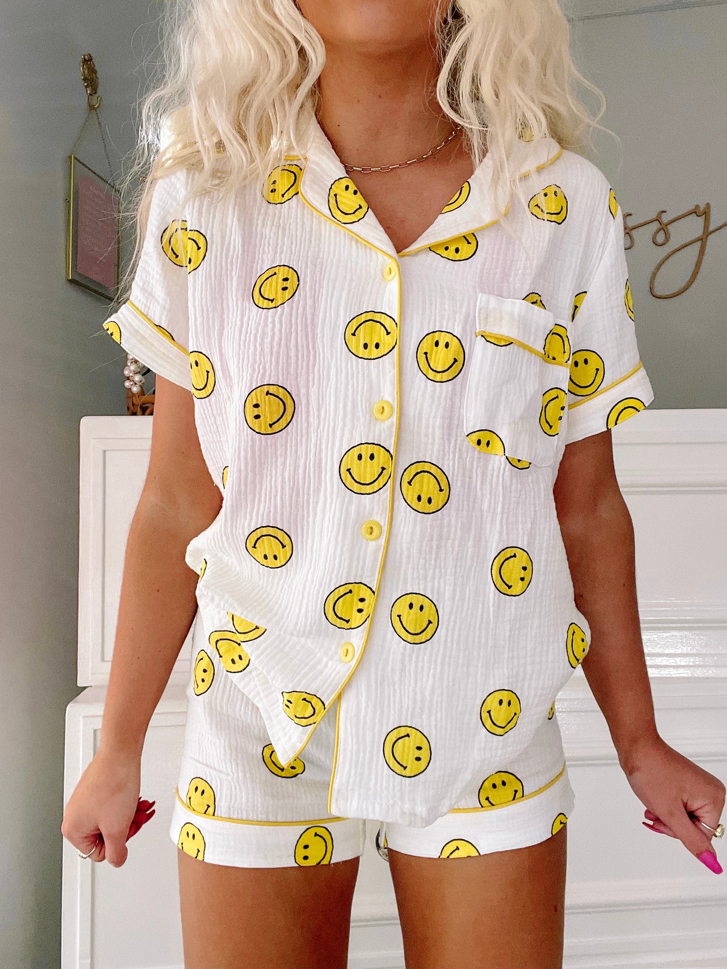 White cotton short pajama set with yellow smiley face print, button-up top and shorts.