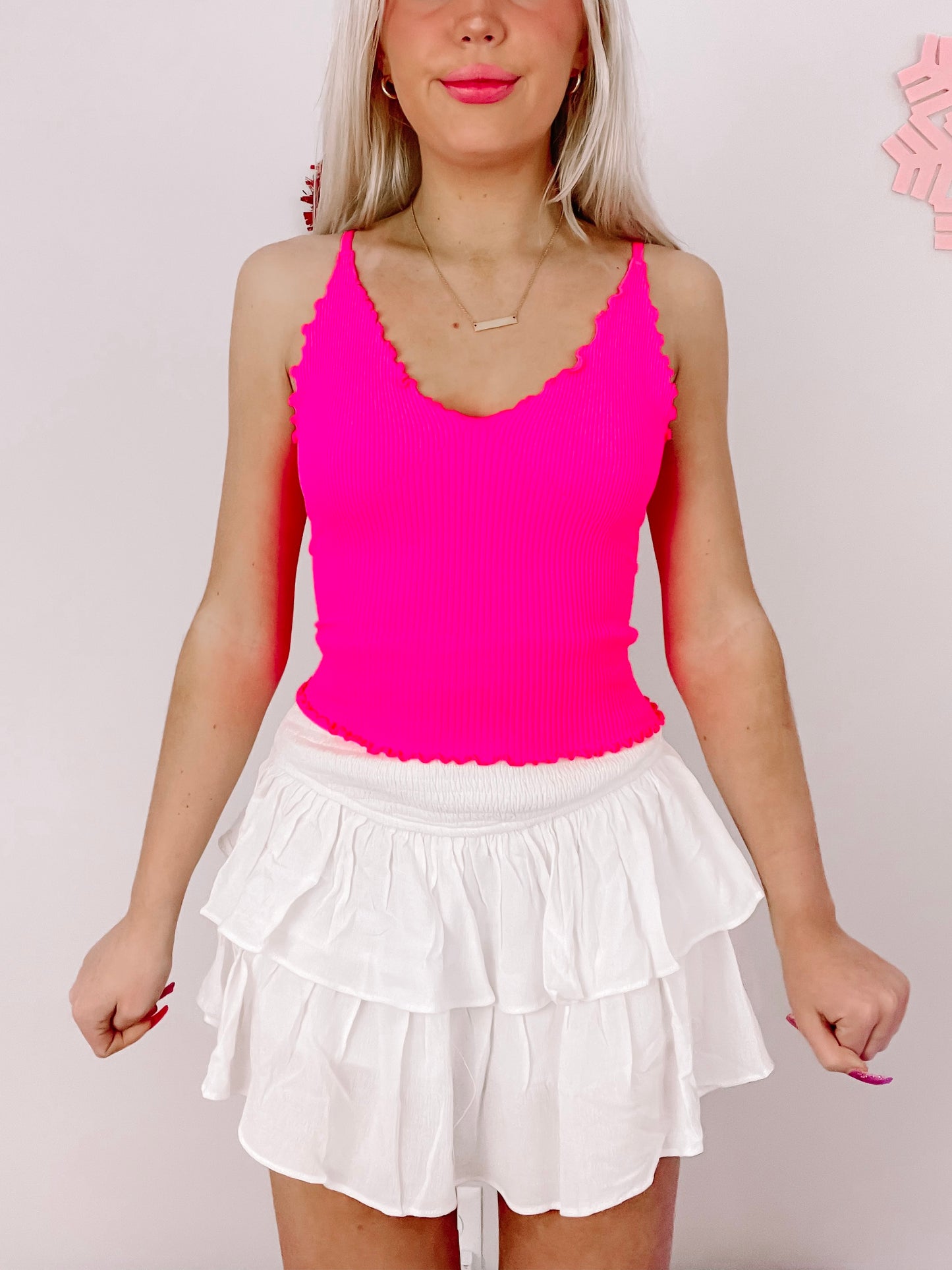 Hot pink ribbed tank top styled with a white tiered ruffle mini skirt.
