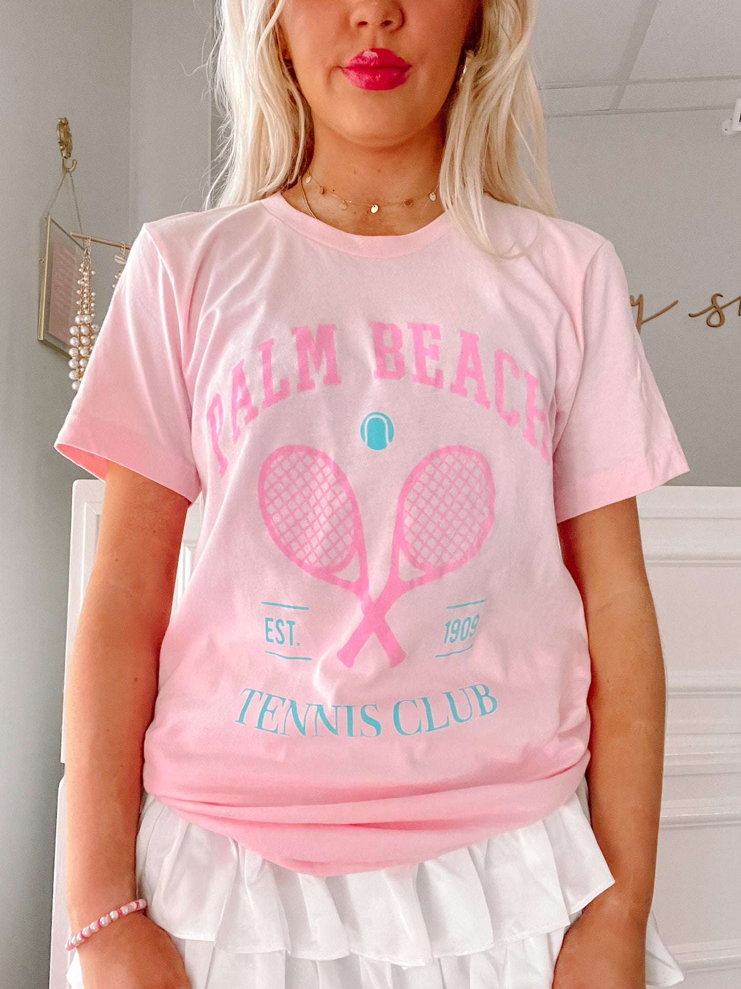Pink tennis tee featuring crossed rackets graphic; light pink, short sleeves.