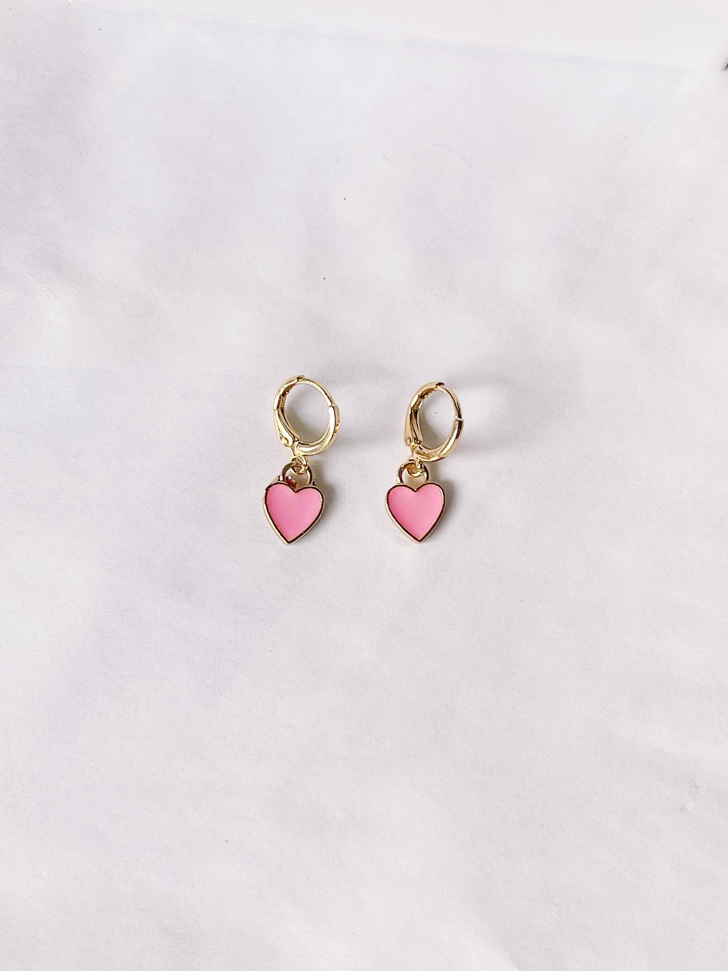 Pink heart dangle earrings with gold hoops, displayed on white background.
