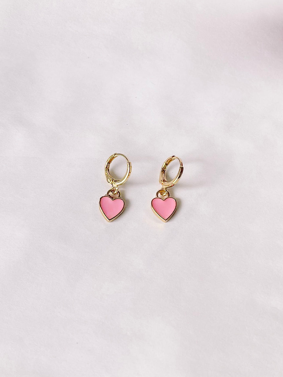 Gold hoop earrings with delicate pink heart charms, displayed on a white background.