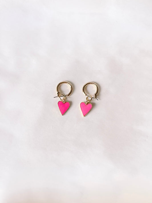 Gold hoop earrings with pink heart charms, shown on a white background.