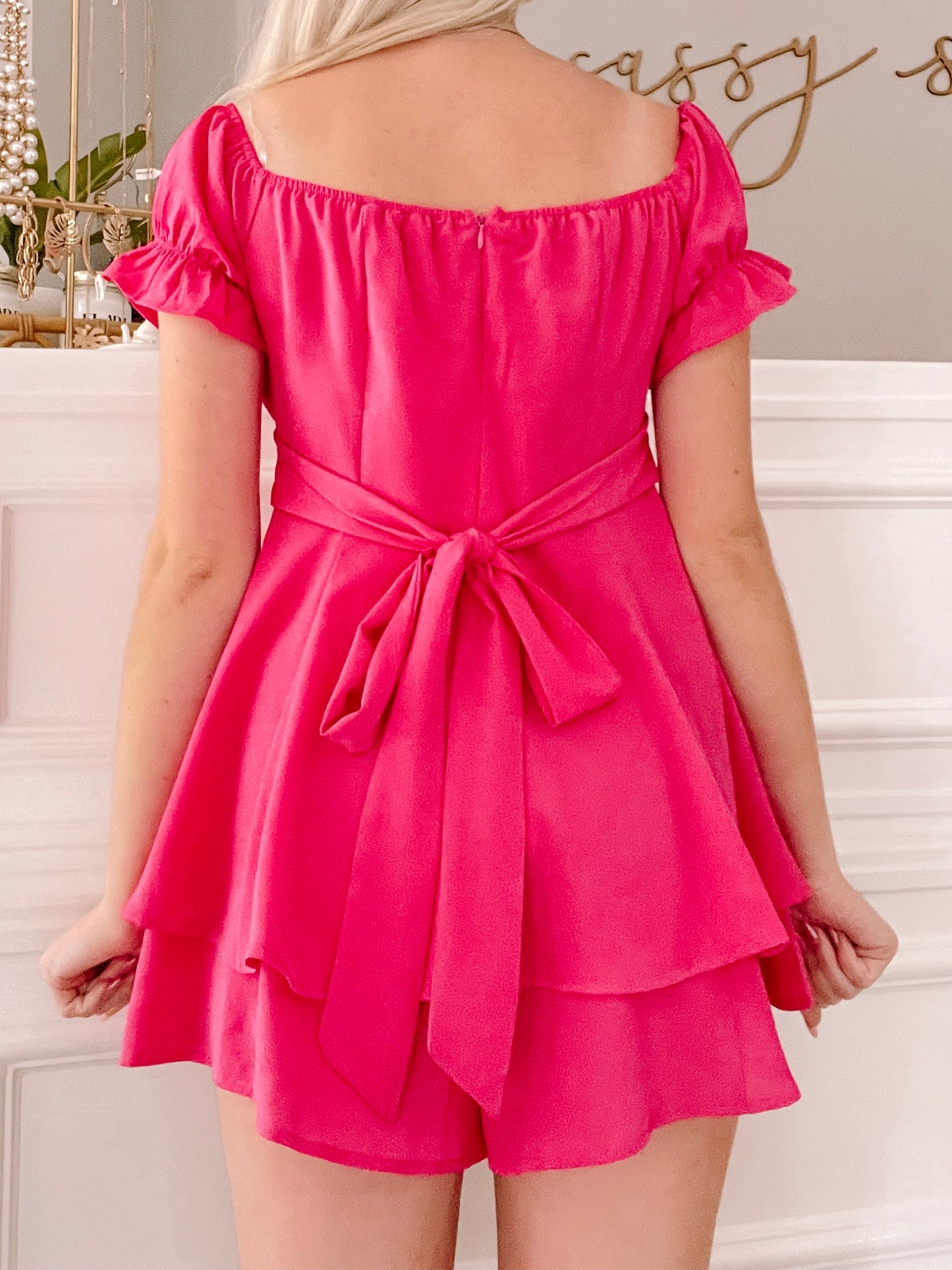 Hot pink romper with tiered skirt and self-tie waist detail.