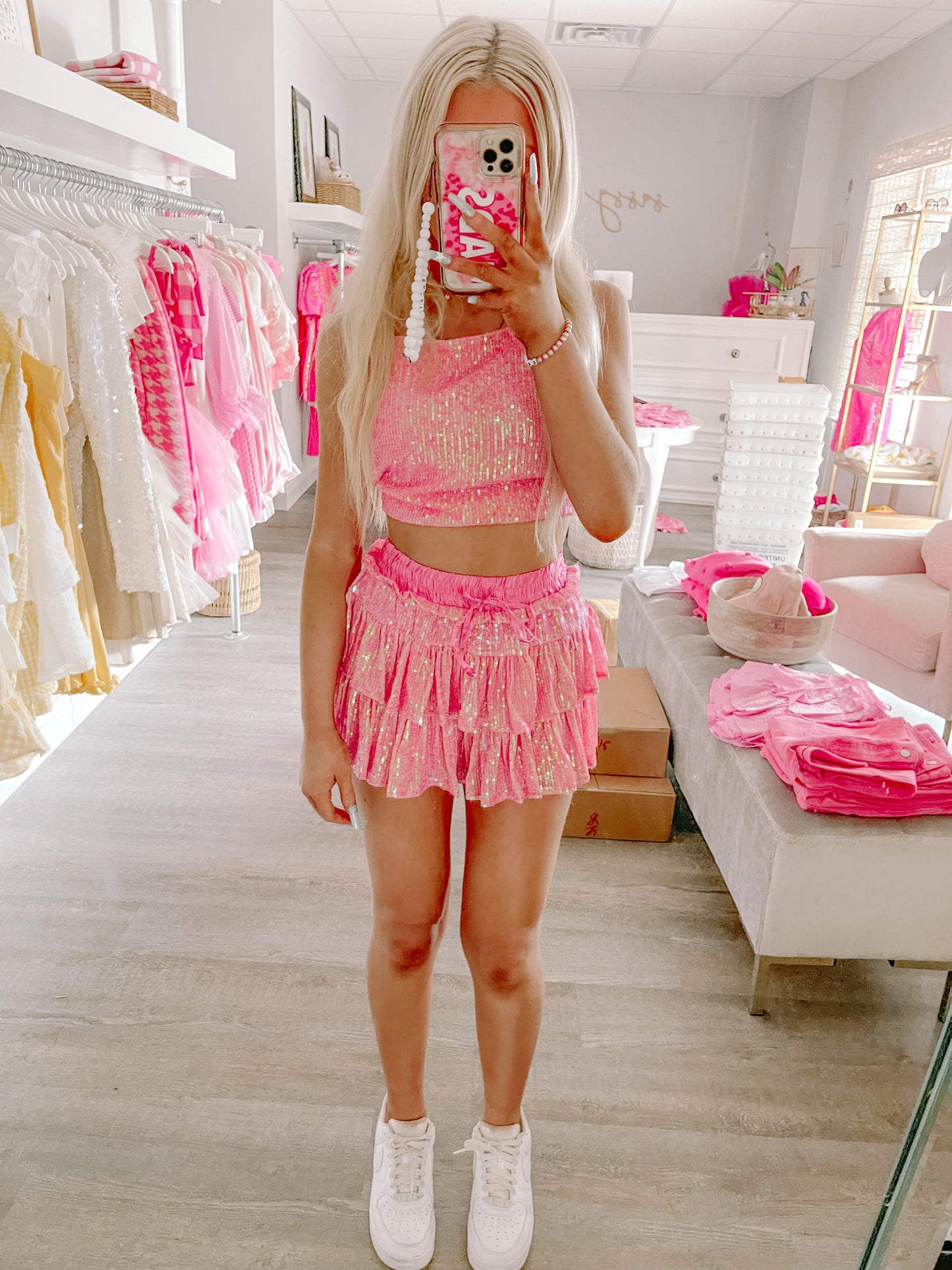 Pink sequin mini skirt with ruffled layers, modeled in a boutique.