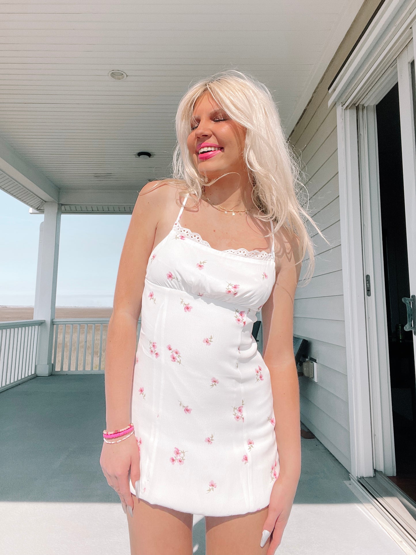 White floral mini dress, perfect for spring; features delicate pink flowers and scalloped neckline.