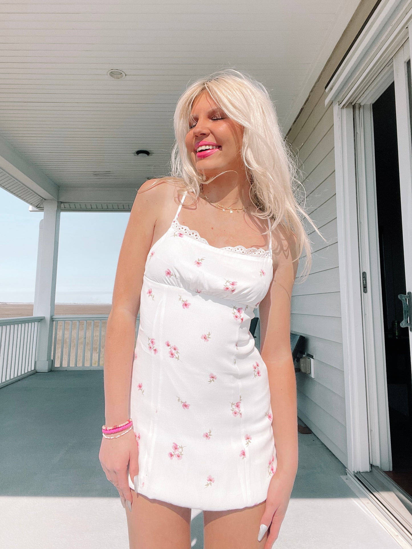 White floral mini dress on a sunny porch.
