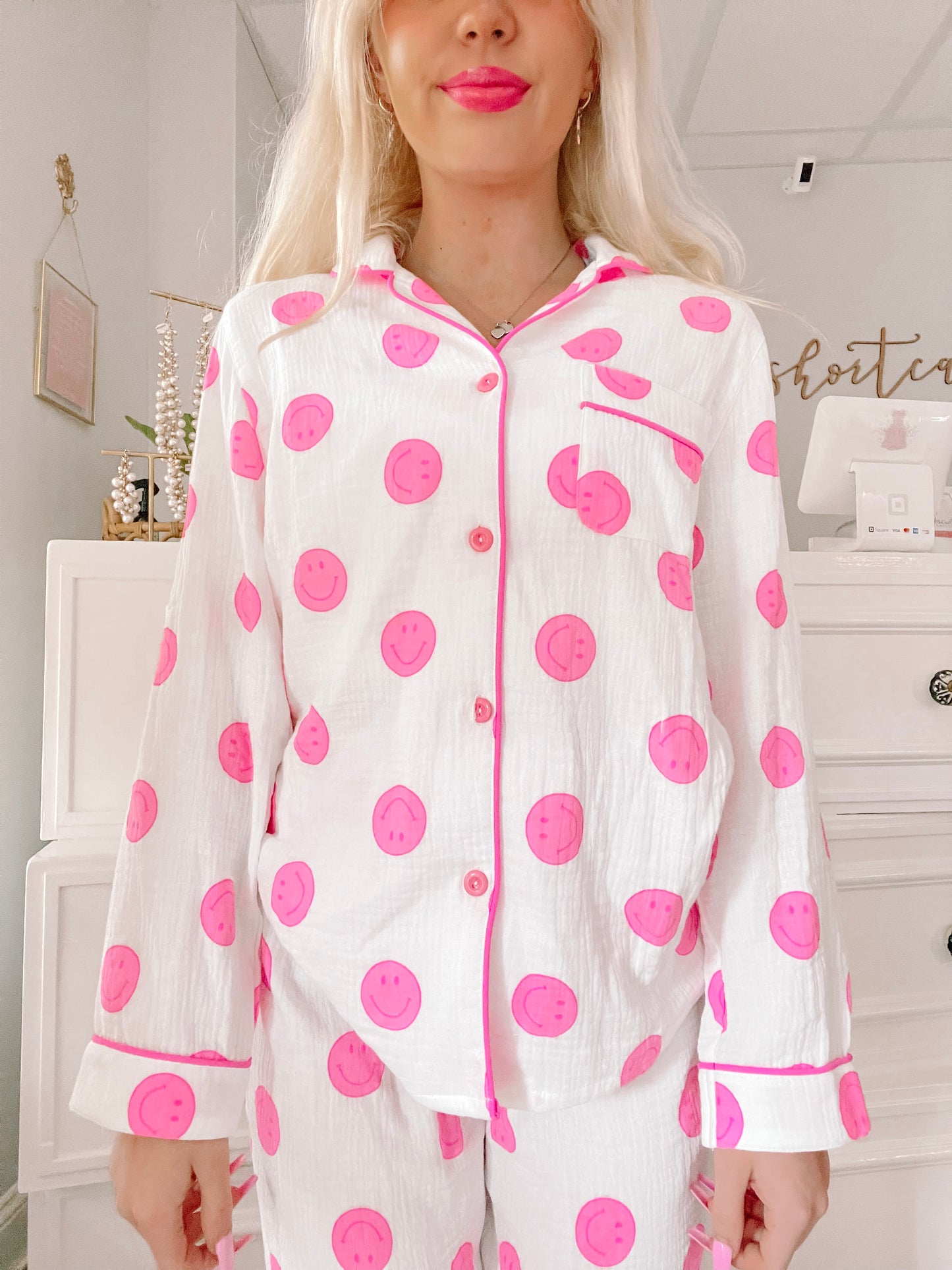 White pajama set with pink smiley faces, button-up top and long sleeves.