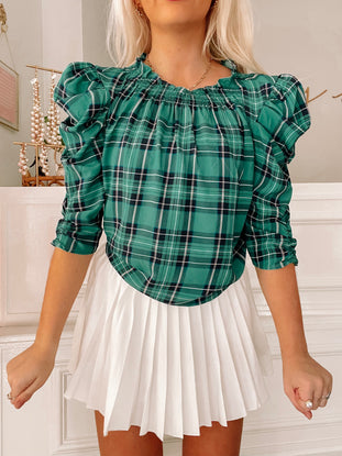 Green plaid blouse with puff sleeves, styled with a white pleated skirt.