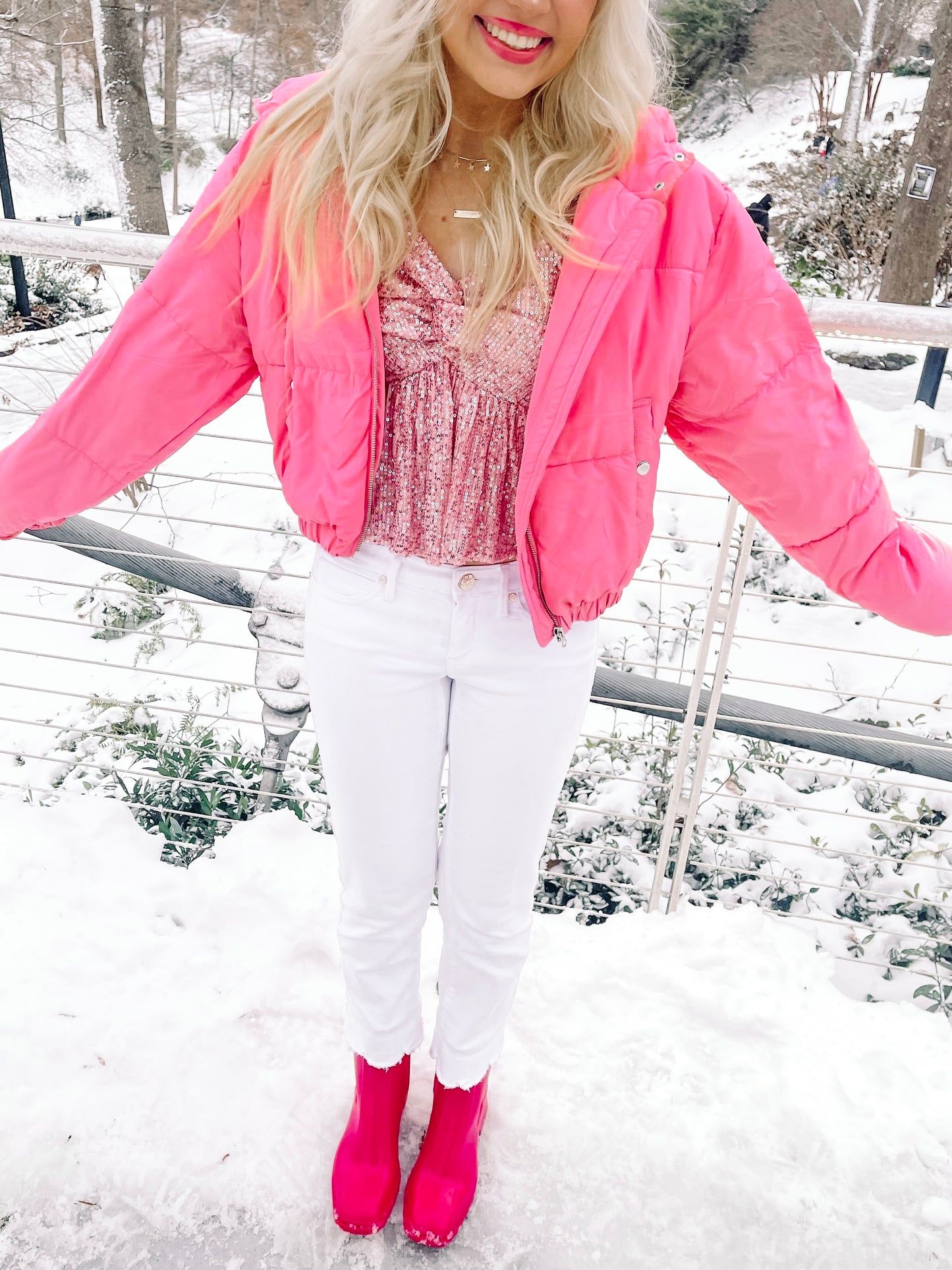Hot pink puffer jacket styled in snowy setting