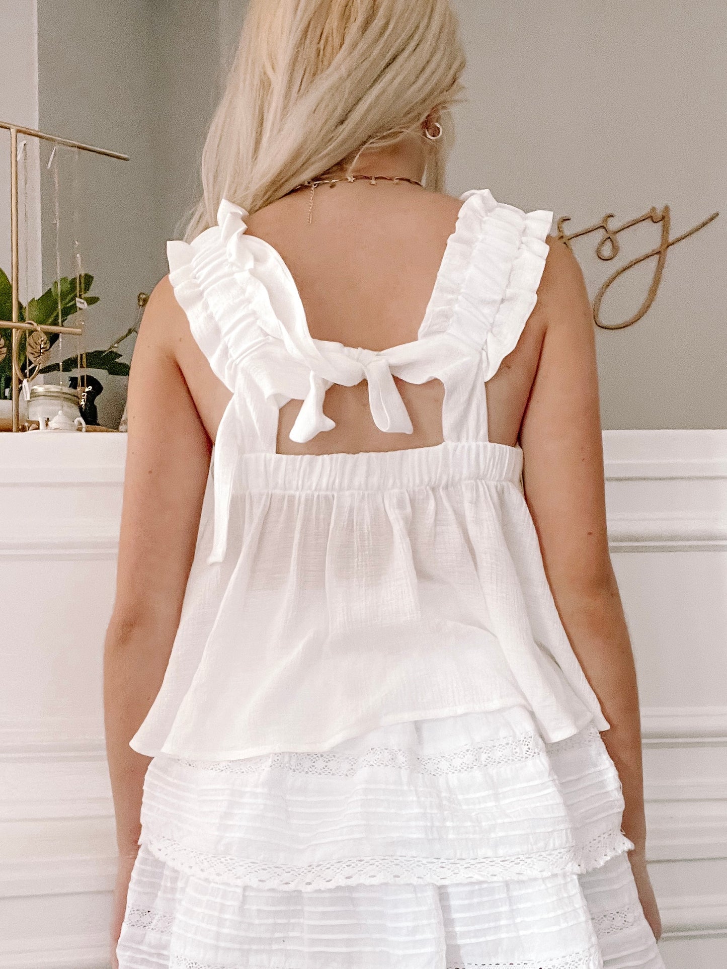 White eyelet peasant top with ruffled straps, tied at the back, shown on model.