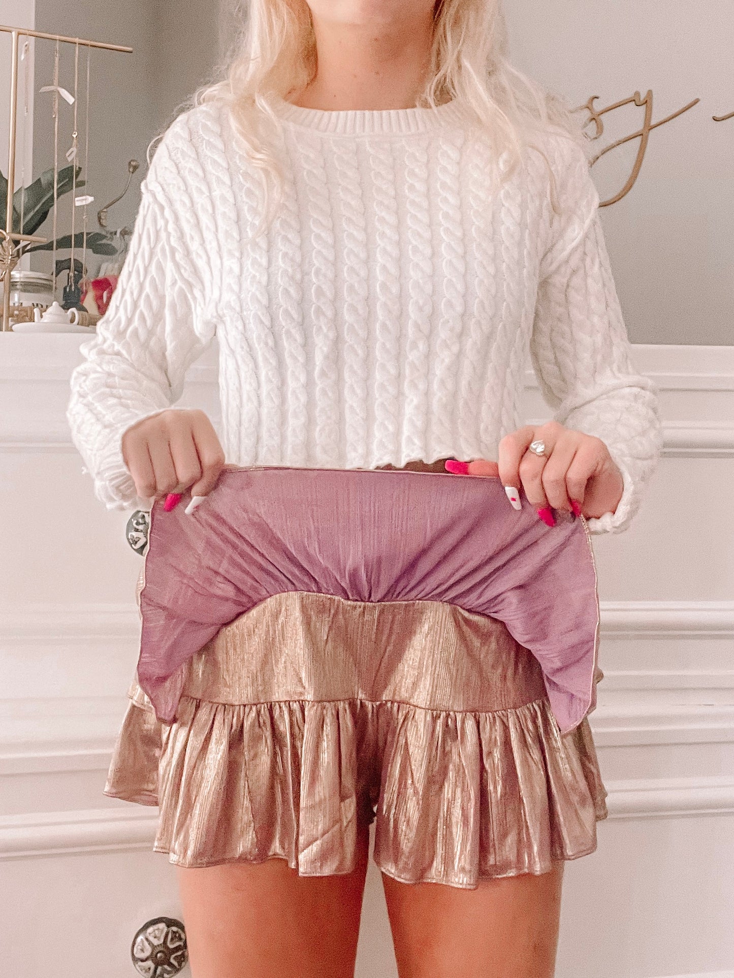Rose gold metallic mini skirt with ruffled hem and lilac lining, shown on a model.