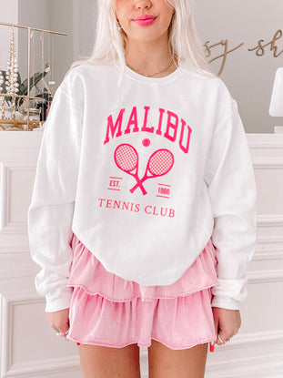 White crewneck sweatshirt with pink tennis club graphic; model wears pink skirt.