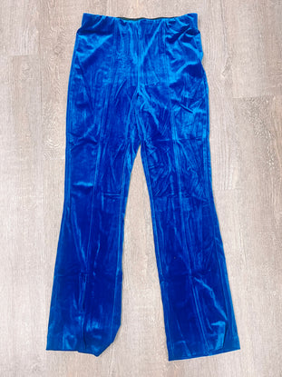 Vibrant blue velvet pants laid flat on wood; luxurious fabric texture.