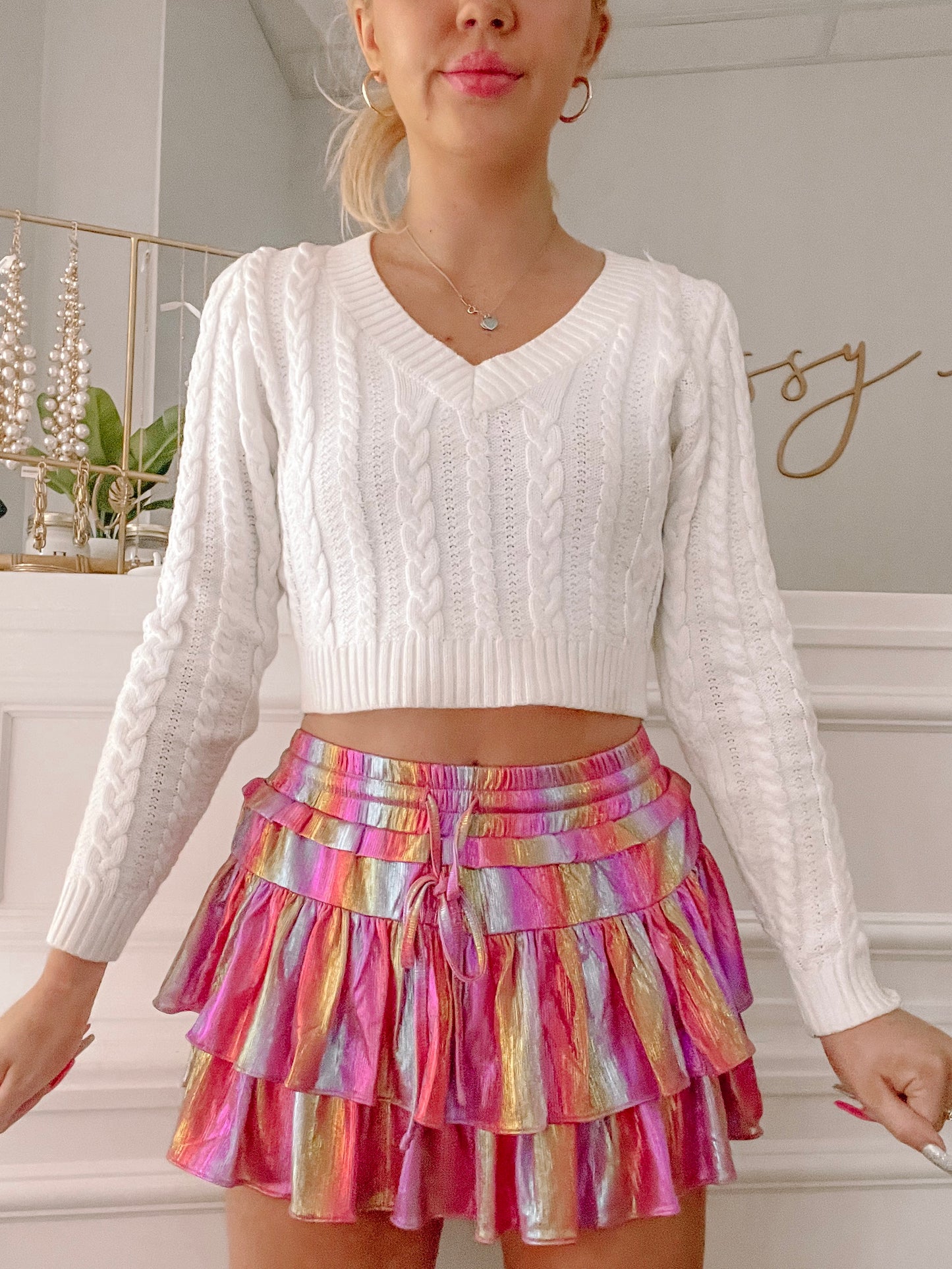White cable knit cropped sweater paired with a vibrant metallic mini skirt.