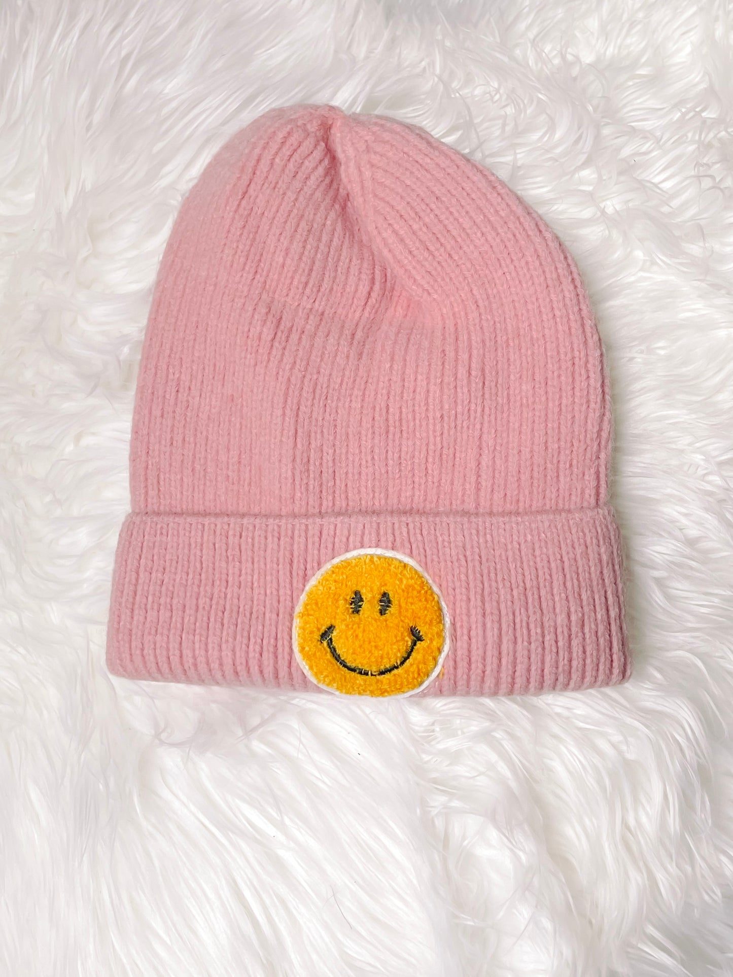 Light pink knit beanie with yellow smiley face patch