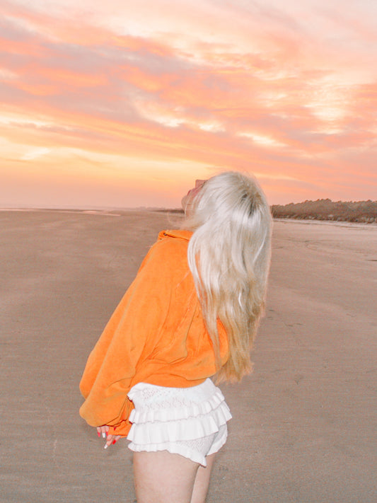 White ruffled shorts worn on a beach at sunset.