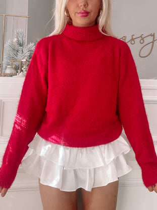 Fuzzy red turtleneck sweater styled with a white ruffled skirt.