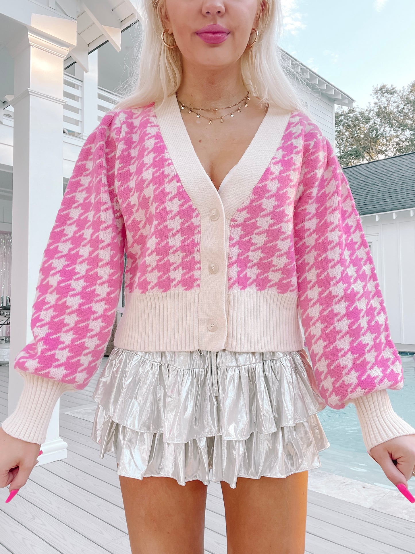 Pink houndstooth knit cardigan with cream trim, button front, and puffy sleeves, modeled outdoors.