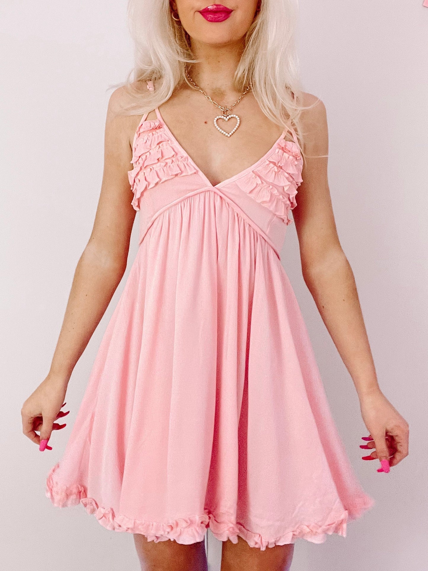 Pink mini dress with ruffled straps and hem, shown on a model.