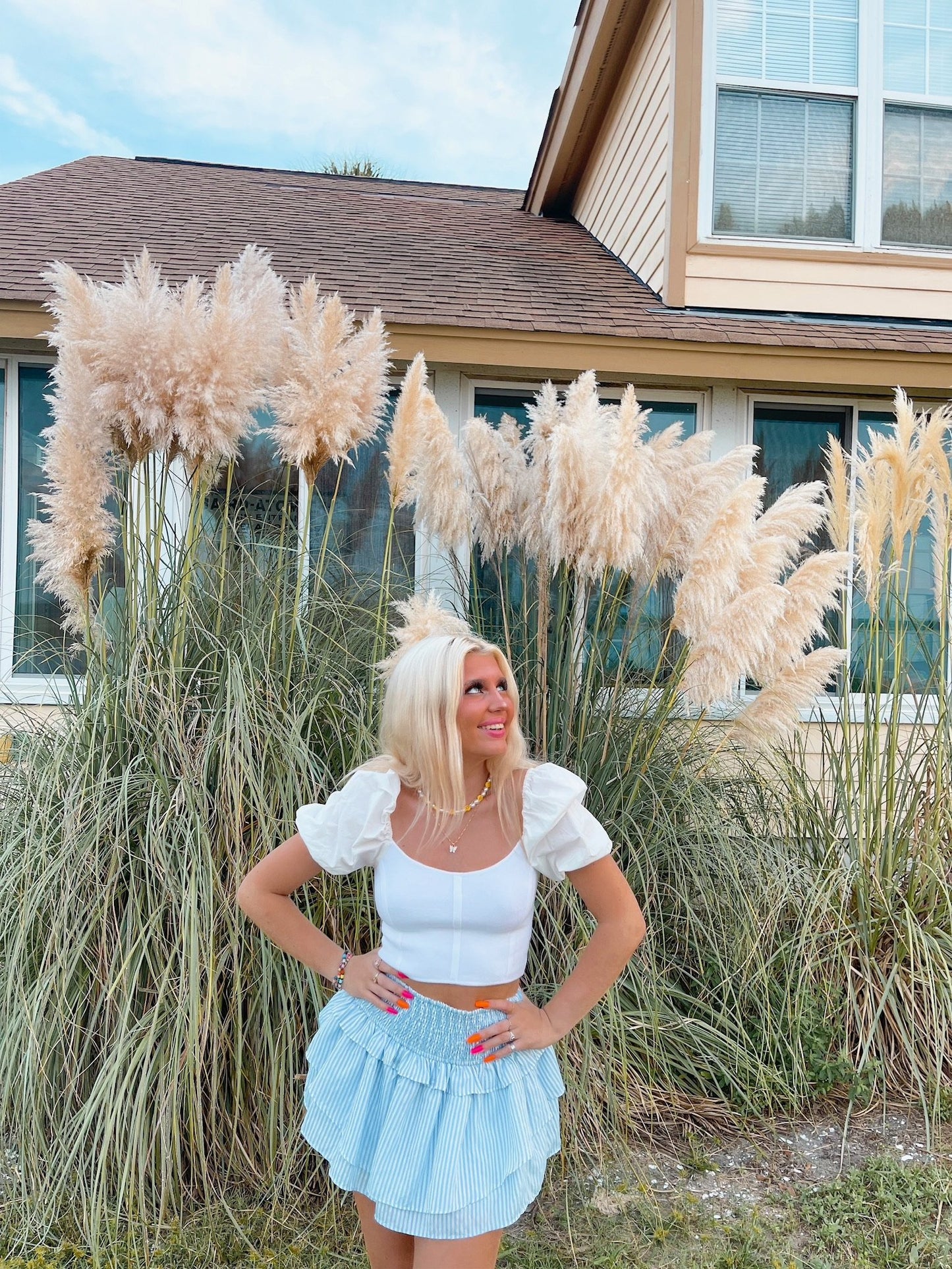 Blue striped ruffle mini skirt outdoors, styled with a white crop top near pampas grass.