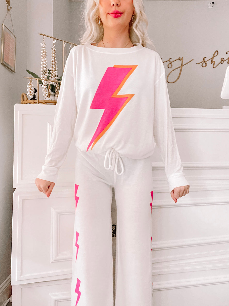 White pajama set with pink and orange lightning bolt print, shown on model.