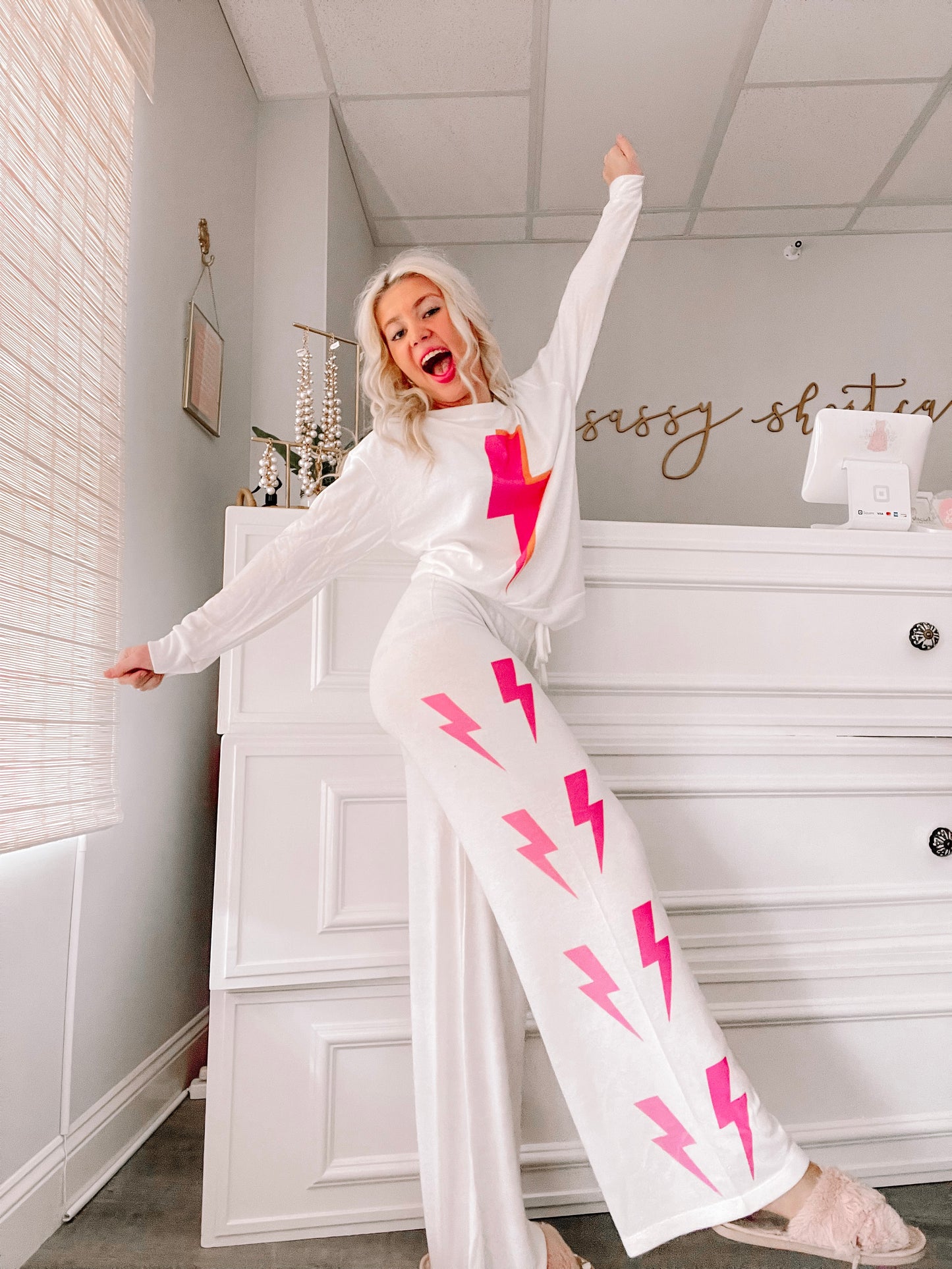 White pajama set with pink lightning bolt print, styled in a bright interior.