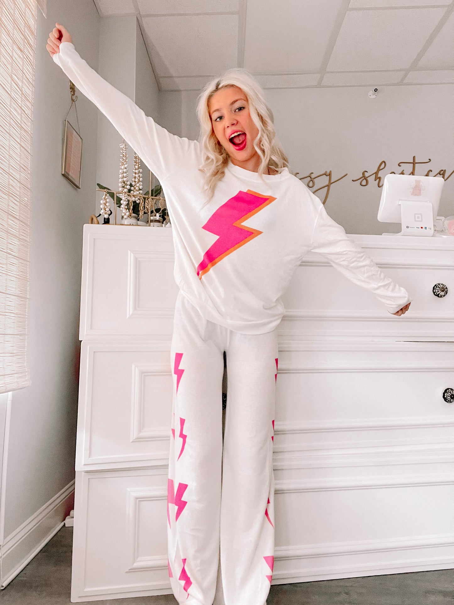 White pajama set with pink lightning bolt print, long sleeves, and wide-leg pants.
