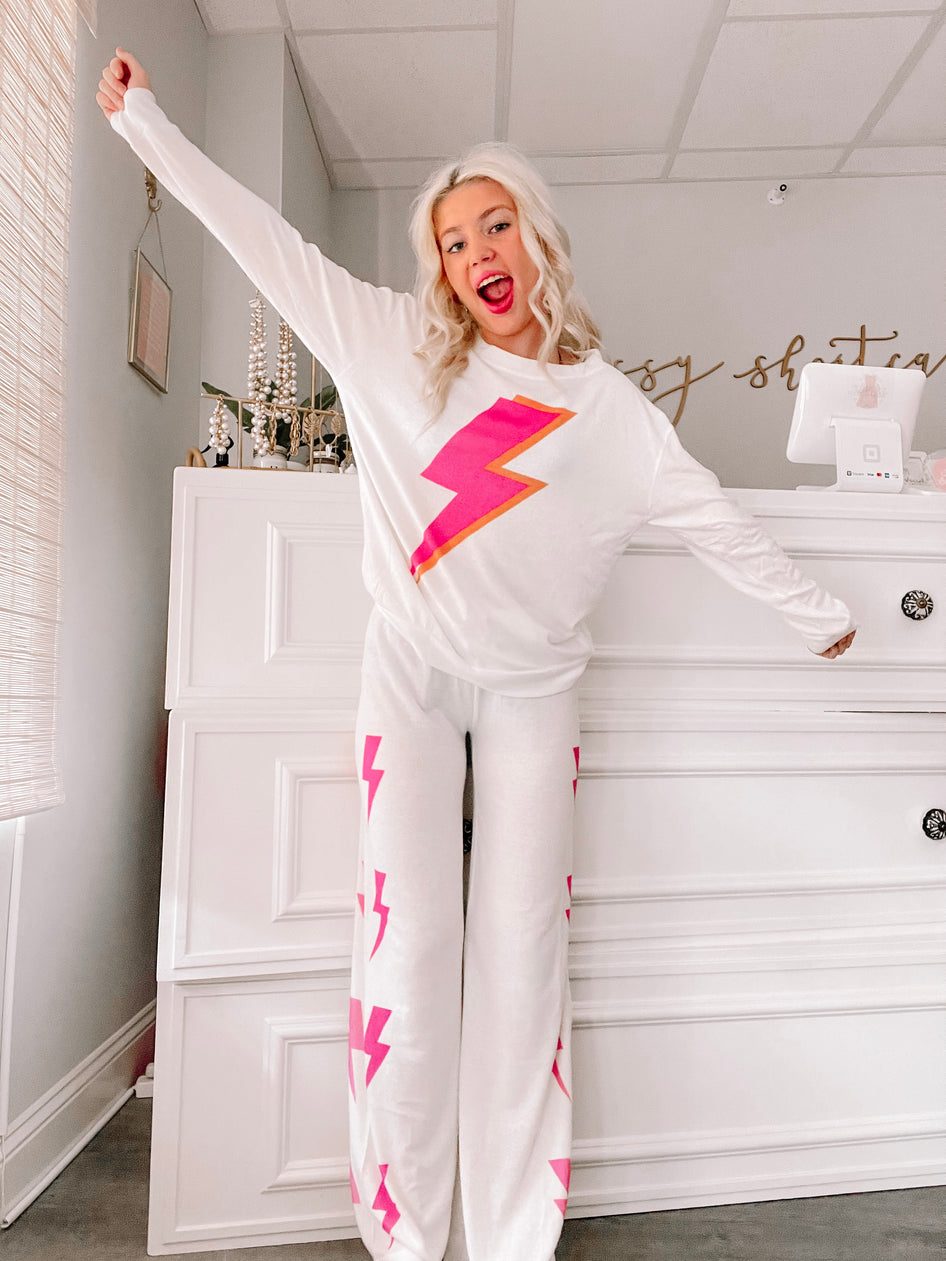White pajama set with pink lightning bolt print, long sleeves, and wide-leg pants.